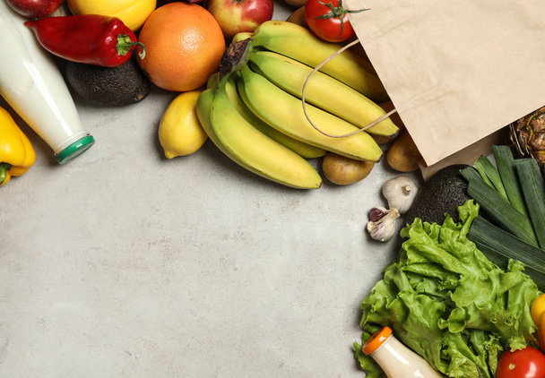 Paper bag with fresh vegetables and fruits on grey background, flat lay. Space for text - Foto, Bild