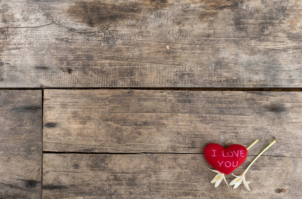 Coeurs rouges "Je t'aime" avec Millingonia sur la table rugueuse en bois. Contexte de la paroi rocheuse. La lumière du soleil brille sur le cadre. Espace de copie pour l'édition et le texte
. - Photo, image