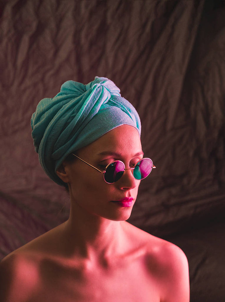 Portrait of girl in neon light, dressed in blue turban on her head and green glasses. - Fotoğraf, Görsel