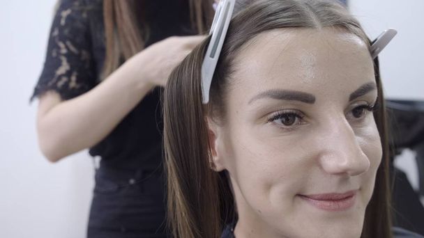 Мила дівчина з довгим брюнеткою перукар робить ламінування волосся в салоні краси. концепція догляду за волоссям
  - Фото, зображення