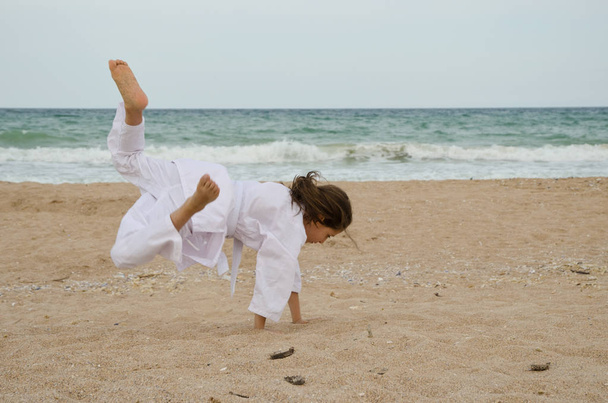 Kid practicing Aikido on the beach. Healthy lifestyle and sports concept - Photo, Image