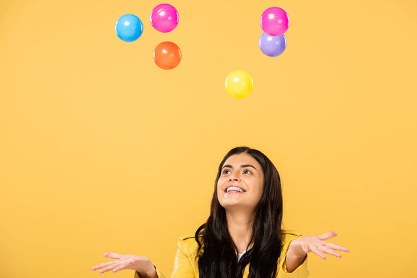 excited girl with colorful balls, isolated on yellow - Фото, изображение