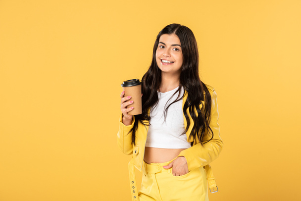 mooie brunette meisje met koffie te gaan geïsoleerd op geel - Foto, afbeelding