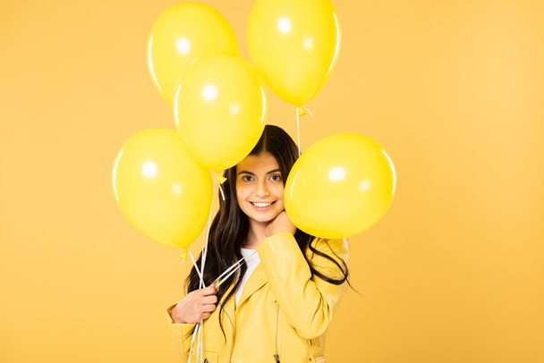 happy girl holding yellow balloons, isolated on yellow - Foto, Imagem