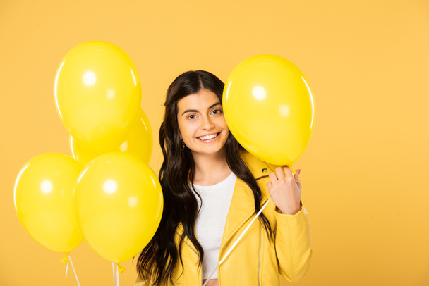 aantrekkelijke vrouw met gele ballonnen, geïsoleerd op geel - Foto, afbeelding