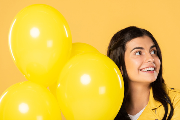 chica feliz sosteniendo globos amarillos, aislado en amarillo
 - Foto, Imagen