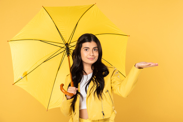 привлекательная девушка позирует с зонтиком, изолированный на желтый
 - Фото, изображение