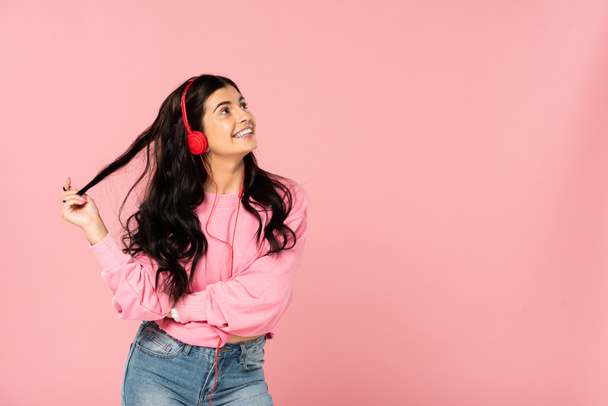 beautiful girl listening music with headphones, isolated on pink - Fotó, kép