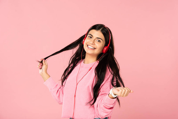 smiling girl listening music with headphones, isolated on pink - Fotoğraf, Görsel