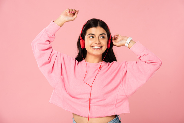 beautiful girl dancing and listening music with headphones, isolated on pink - Foto, afbeelding
