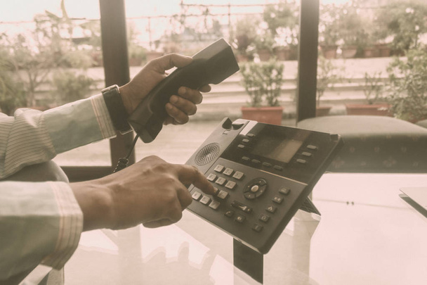 Nahaufnahme Mann der Hand hält Telefonhörer und wählt eine Telefonnummer, um einen Anruf mit Festnetztelefon für Geschäftsgespräche zu tätigen. Globale Kommunikation, Business Support, Kundenbetreuungskonzept. - Foto, Bild