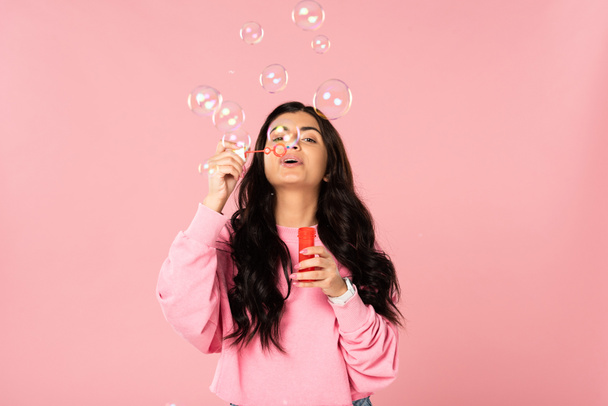 attraktives Mädchen bläst Seifenblasen isoliert auf rosa - Foto, Bild