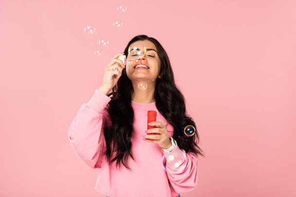 lustiges Mädchen pustet Seifenblasen isoliert auf rosa - Foto, Bild