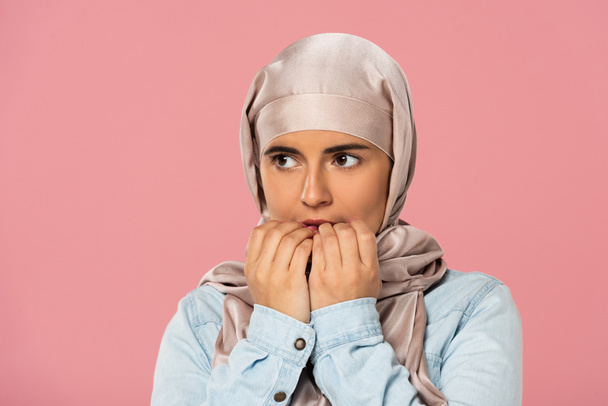 hijab ısırma çivi güzel korkmuş müslüman kız, pembe izole - Fotoğraf, Görsel