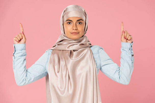 young arabic woman in hijab pointing up, isolated on pink  - Fotografie, Obrázek