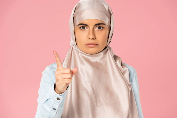 serious muslim woman in hijab pointing at you, isolated on pink  - Photo, Image