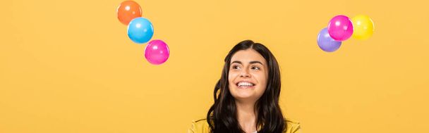 happy attractive girl with colorful balls, isolated on yellow - Φωτογραφία, εικόνα