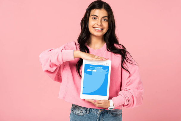 KYIV, UKRAINE - JULY 30, 2019: smiling girl holding digital tablet with twitter app on screen, isolated on pink - Φωτογραφία, εικόνα