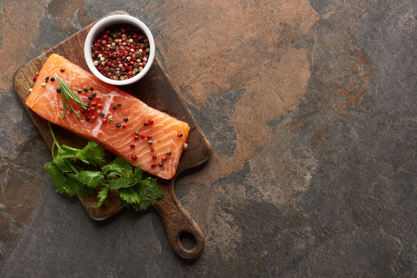 top view of raw fresh salmon with peppercorns, parsley on wooden cutting board - Φωτογραφία, εικόνα