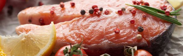 Close-up uitzicht op rauwe zalm steak met peperkorrels, citroen en rozemarijn, panoramische foto - Foto, afbeelding