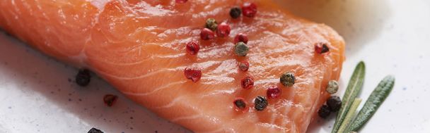 close up view of raw salmon steak with peppercorns on plate, panoramic shot - Foto, Imagem