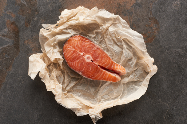 вид сырого стейка лосося на булочной бумаге на каменном столе
 - Фото, изображение