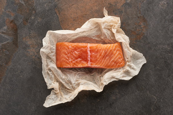 top view of uncooked salmon steak on bakery paper on stone table - Photo, Image