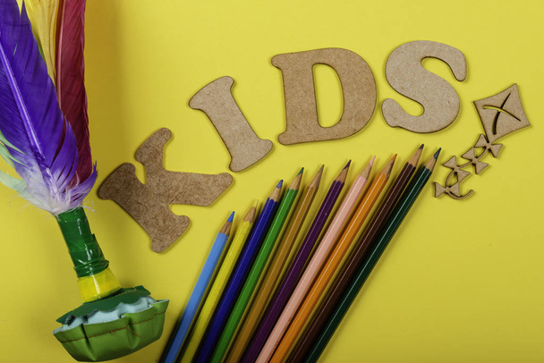 Шаттл с красочными перьями на желтом фоне и разноцветными карандашами и с письменным текстом для детей
. - Фото, изображение