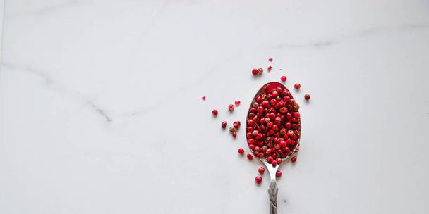 Pink pepper in spoon on stone background. Spice closeup top view - Photo, Image