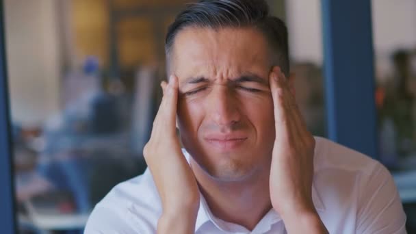 Vermoeide kantoormedewerker met hoofdpijn. Gestresste zakenman in wit shirt voelt hoofdpijn en masserende hoofd om te ontspannen en pijn te verminderen, binnen, close-up. - Video