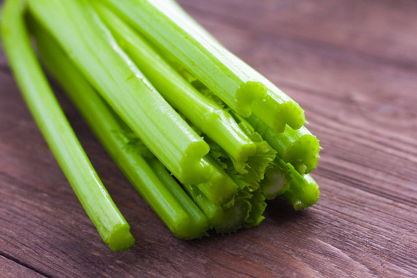 Celery closeup on wooden background. Stems of fresh organic green celery closeup. Healthy eating, diet concept - Photo, Image