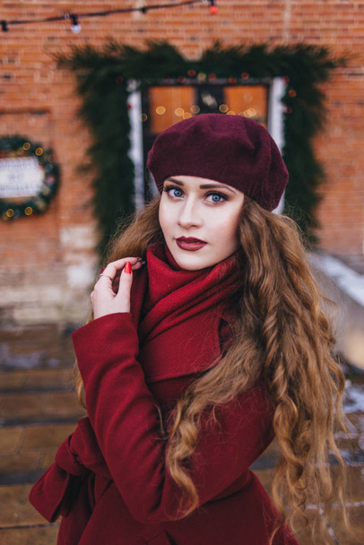 A beautiful girl in a red coat and a beret is walking along the  - Photo, Image