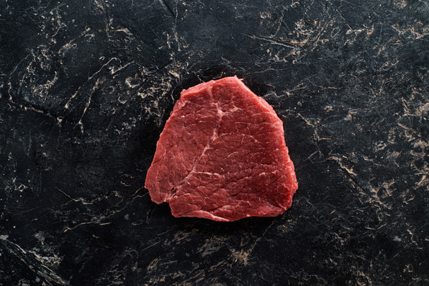 top view of raw meat steak on black marble surface - Photo, Image