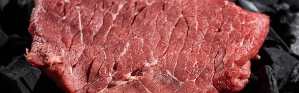 panoramic shot of fresh raw beef fillet on coal pieces - Photo, Image