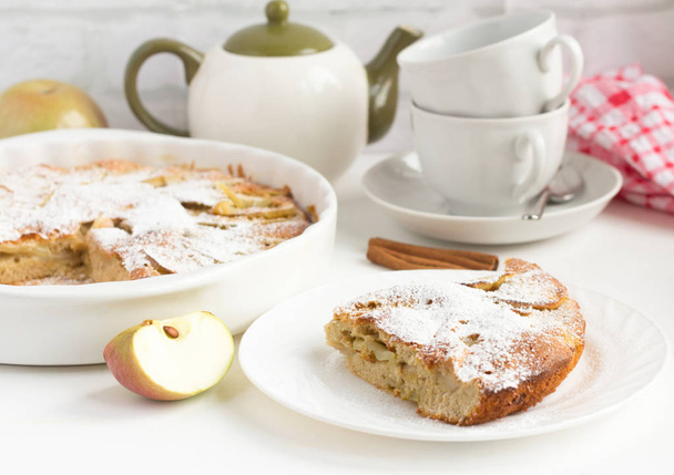 kotitekoisia omenapiirakka kanelilla ja astiat teetä pöydälle
 - Valokuva, kuva