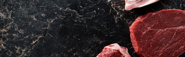 plano panorámico de las partes de carne sin cocer en la superficie de mármol negro
 - Foto, Imagen