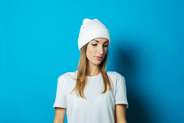 junge Frau mit weißem Hut und T-Shirt auf blauem Hintergrund - Foto, Bild