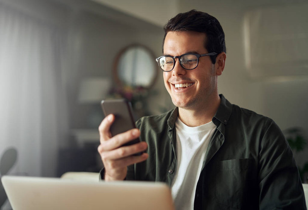 Man smiling while texting messages on mobile phone - Foto, afbeelding