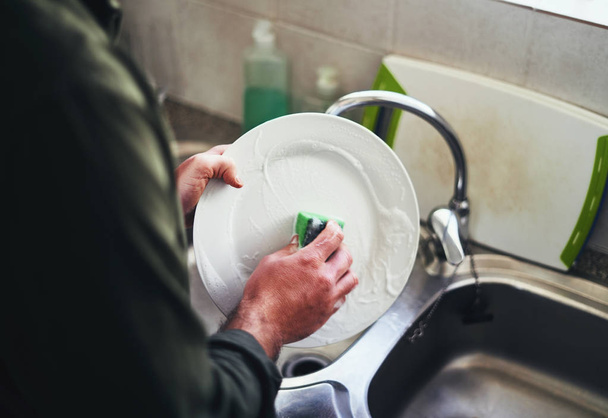 Close-up of a man washing the ceramic dish in the kitchen sink - Foto, imagen