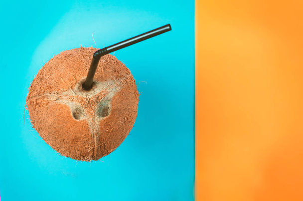 Coconut with black straw on neon bright blue and orange background in vaporwave webpunk style. Summer concept tropical flat lay. Fashion minimalism surrealism in fruits  - Photo, Image