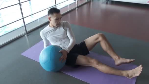 A young Asian is training in the kickboxing gym. warm up. Kickboxer athlete is actively warming up before hard training in the gym using various shells - Felvétel, videó