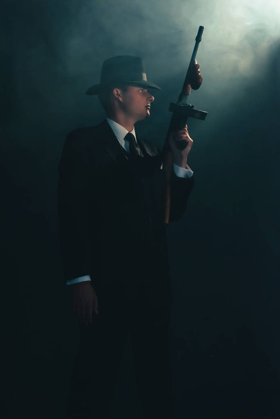 Ретро-гангстер стоит с пулеметом в тумане
. - Фото, изображение