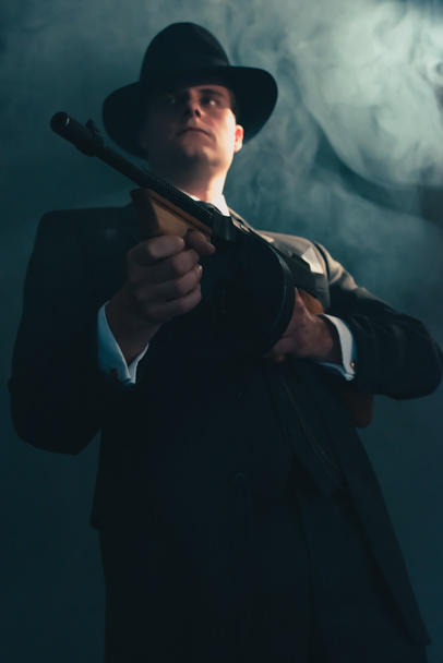 Retro-Gangster mit Hut schießt in nebliger Nacht mit Maschinengewehr. - Foto, Bild