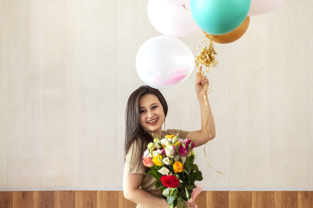 Portrait of charming, pretty girl holding bouquet of flowers and hot air balloons - Photo, Image