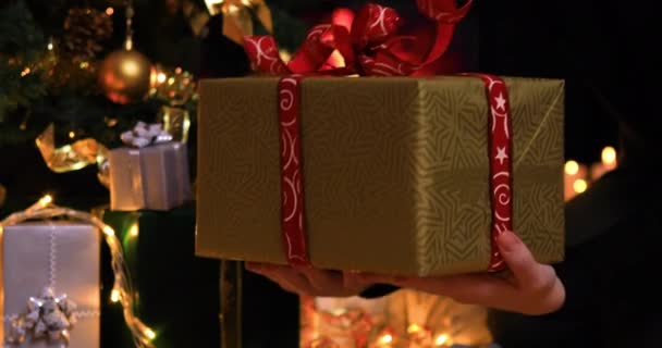 Noel ağacı ve şömine yakınında Noel hediyesi gösteren kız. Tatil konsepti için hediye vermek. 4k - Video, Çekim
