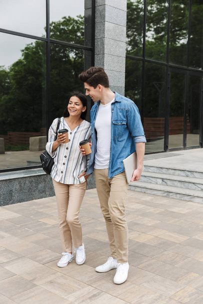Feliz animado incrível casal amoroso estudantes ao ar livre fora na rua andando bebendo café conversando uns com os outros
. - Foto, Imagem