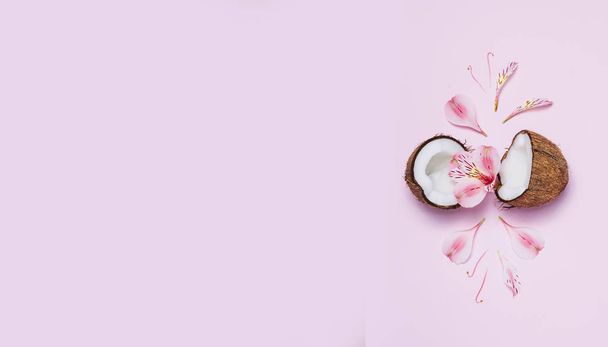 Broken coconut with tropic flowers on pink background. - Foto, immagini
