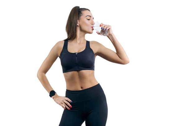 Isolated portrait of young woman in sportswear drinking water - Photo, image