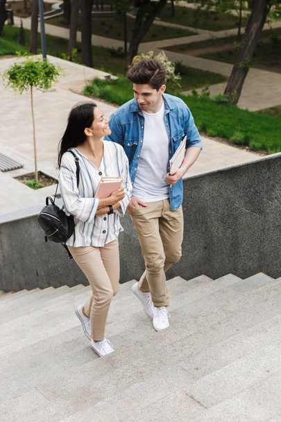 Incrível casal amoroso estudantes ao ar livre fora andando por passos com livros
. - Foto, Imagem