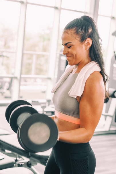 Woman lifting weights dumbbells action of lift captured. - Foto, afbeelding
